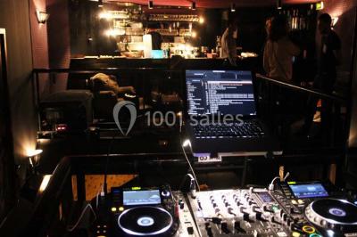 Personne en costume buvant un verre dans un bar faiblement éclairé, avec des lumières floues en arrière-plan.