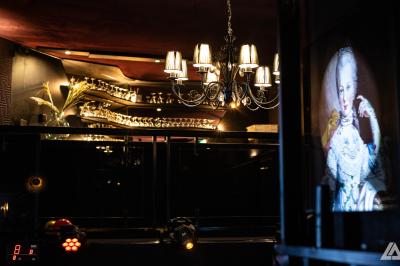 Personne en costume buvant un verre dans un bar faiblement éclairé, avec des lumières floues en arrière-plan.