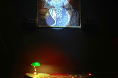 Miniature Location salle Paris 6 (Paris) - Le Scarlett #23 Portrait éclairé d'une femme en tenue d'époque, suspendu au-dessus d'une table ronde avec une lampe verte allumée.