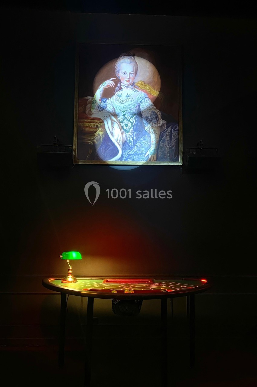 Portrait éclairé d'une femme en tenue d'époque, suspendu au-dessus d'une table ronde avec une lampe verte allumée.