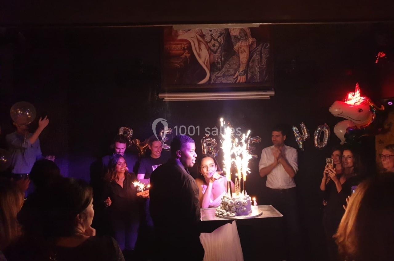 Un couple souffle des bougies sur un gâteau avec des cierges étincelants lors d'une fête en soirée.