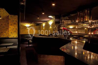 Étagères remplies de verres illuminés par des lumières tamisées dans un bar à l'ambiance sombre.