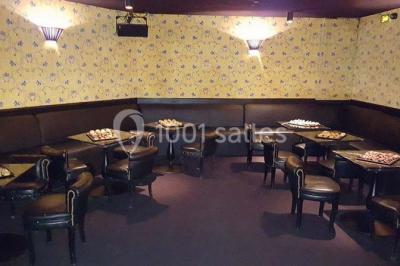 Étagères remplies de verres illuminés par des lumières tamisées dans un bar à l'ambiance sombre.