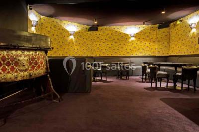 Étagères remplies de verres illuminés par des lumières tamisées dans un bar à l'ambiance sombre.