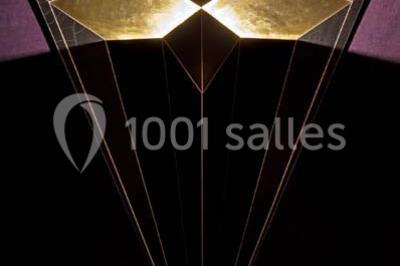 Étagères remplies de verres illuminés par des lumières tamisées dans un bar à l'ambiance sombre.