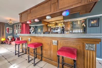 Salle décorée pour un événement avec longues tables dressées, nappes blanches, nœuds roses et portraits accrochés au mur.
