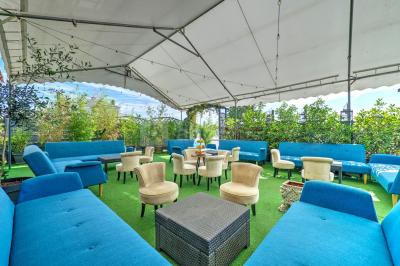 Salle décorée pour un événement avec longues tables dressées, nappes blanches, nœuds roses et portraits accrochés au mur.