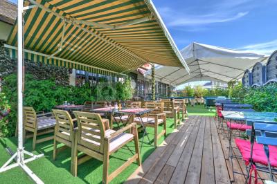 Salle décorée pour un événement avec longues tables dressées, nappes blanches, nœuds roses et portraits accrochés au mur.