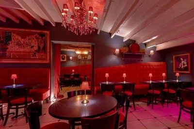 Terrasse extérieure avec tables et chaises en bois sous des auvents, entourée de verdure et de ciel dégagé.