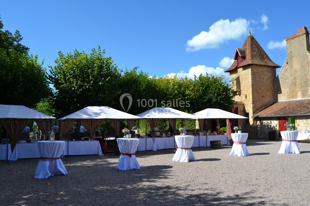 4 petits barnums fournis gratuitement pour l'apéritif Tentes blanches et tables dressées dans une cour pavée, près d'un bâtiment en pierre avec une tour.