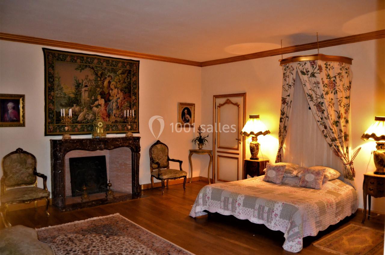 Chambre Pompadour Chambre élégante avec lit à baldaquin, cheminée ornée, tapis au sol et mobilier ancien dans une ambiance chaleureuse.