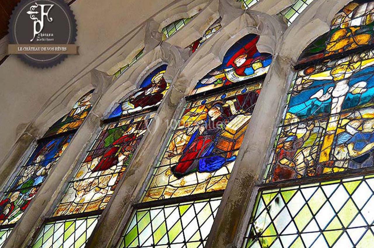 Chapelle du château Vitraux colorés représentant des scènes religieuses dans une église, encadrés par des arches en pierre.