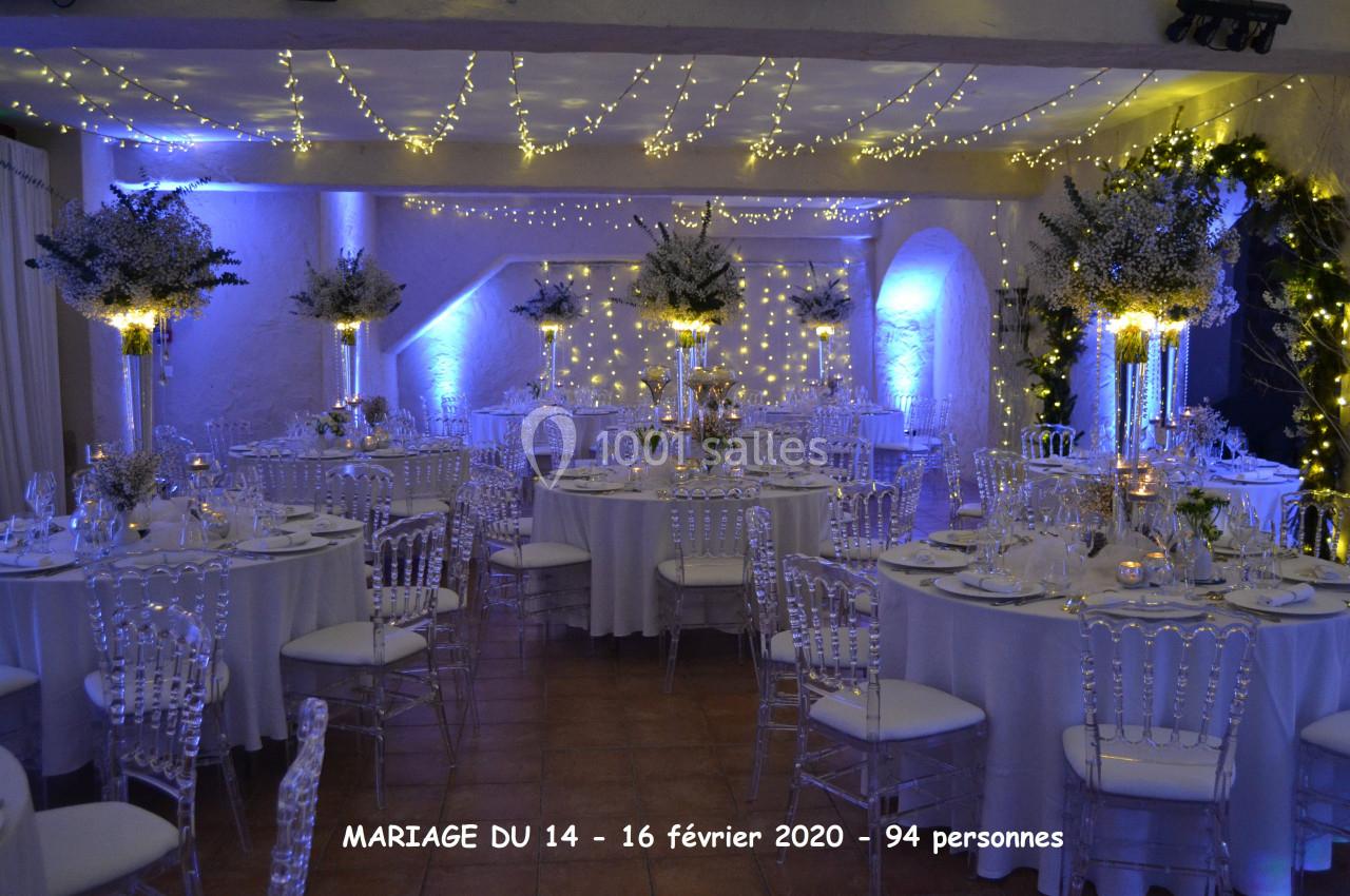 Salle de mariage 110 personnes autour de tables Salle de réception décorée pour un mariage, avec tables rondes, chaises transparentes et éclairage tamisé.