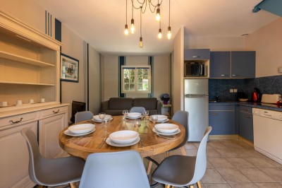 Deux lits simples avec draps blancs, séparés par une table de chevet en bois, éclairés par deux appliques murales.