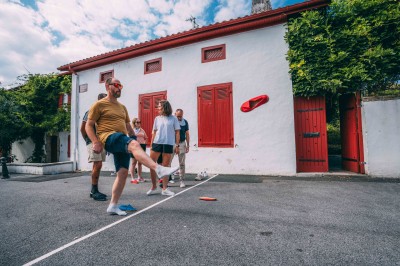 Deux lits simples avec draps blancs, séparés par une table de chevet en bois, éclairés par deux appliques murales.