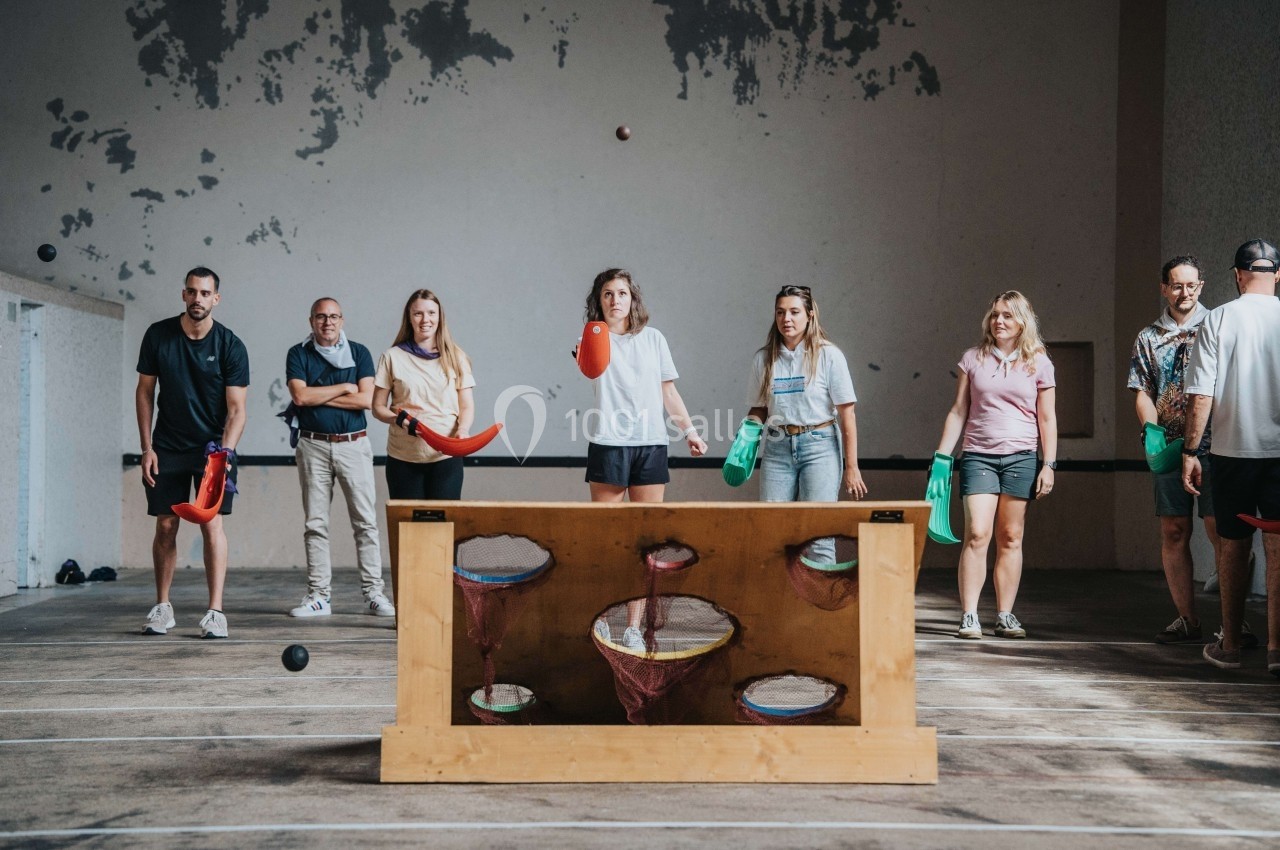 Des personnes jouent à un jeu d'adresse en intérieur, lançant des objets vers des cibles colorées dans un cadre décontracté.