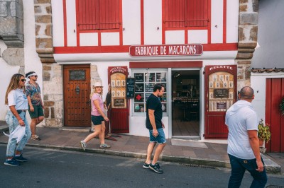 Deux lits simples avec draps blancs, séparés par une table de chevet en bois, éclairés par deux appliques murales.