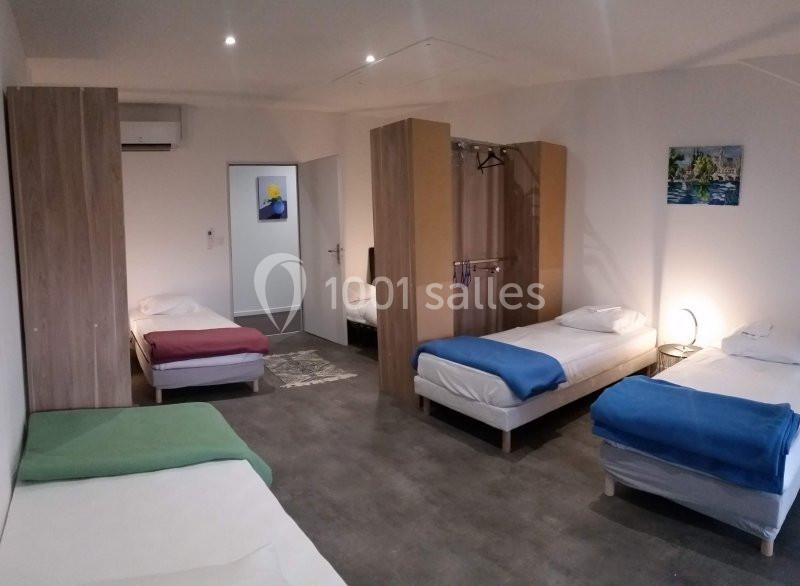 Chambre spacieuse avec quatre lits simples, séparations en bois, éclairage doux et décoration murale.