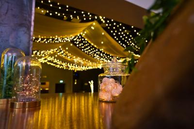 Lit double avec draps blancs, coussins décoratifs noirs et blancs, lampe de chevet allumée et tableau mural coloré.