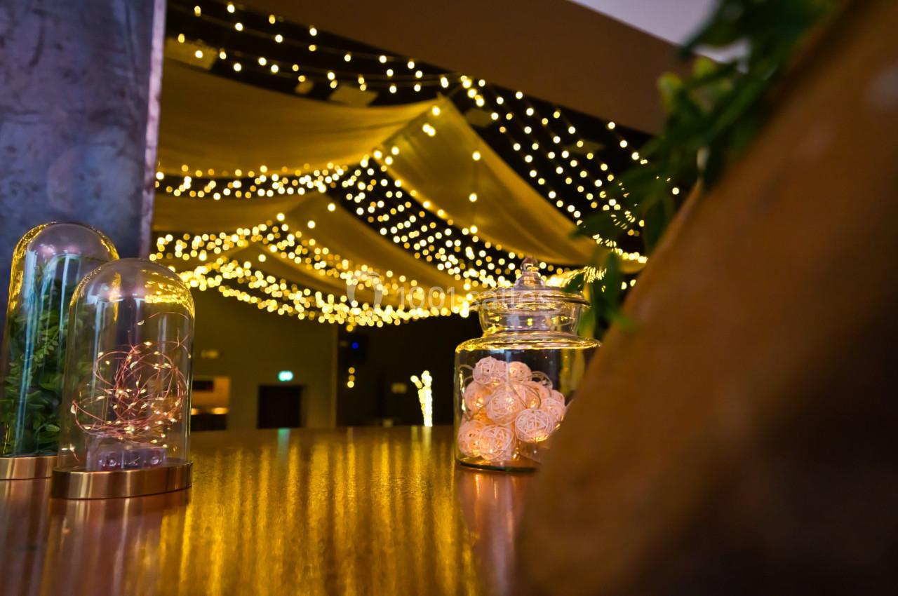 Guirlandes lumineuses suspendues créant une ambiance chaleureuse dans un espace intérieur décoré.