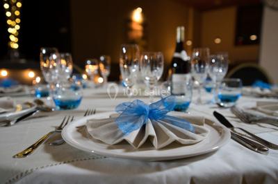 Lit double avec draps blancs, coussins décoratifs noirs et blancs, lampe de chevet allumée et tableau mural coloré.