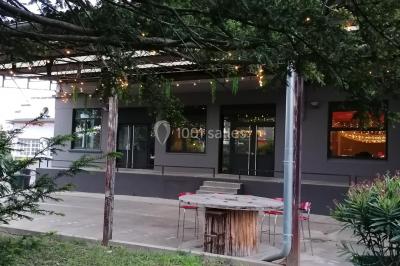 Lit double avec draps blancs, coussins décoratifs noirs et blancs, lampe de chevet allumée et tableau mural coloré.