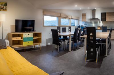 Lit double avec draps blancs, coussins décoratifs noirs et blancs, lampe de chevet allumée et tableau mural coloré.