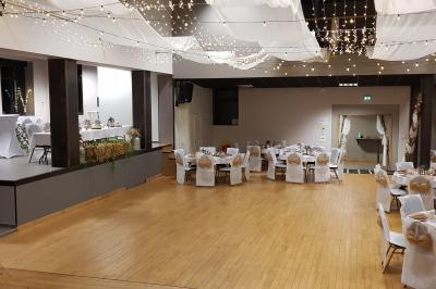 Lit double avec draps blancs, coussins décoratifs noirs et blancs, lampe de chevet allumée et tableau mural coloré.