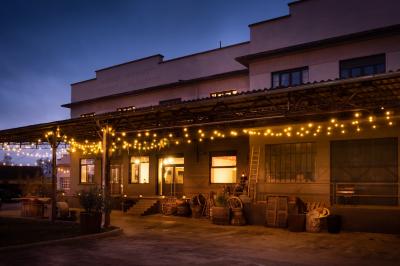 Lit double avec draps blancs, coussins décoratifs noirs et blancs, lampe de chevet allumée et tableau mural coloré.