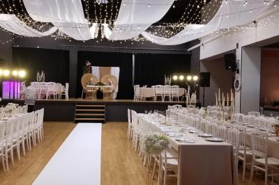 Lit double avec draps blancs, coussins décoratifs noirs et blancs, lampe de chevet allumée et tableau mural coloré.