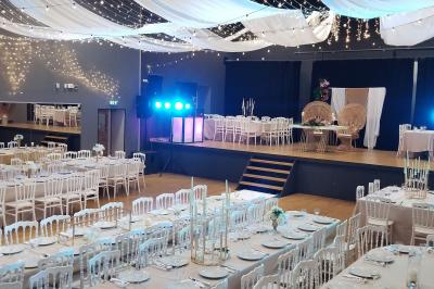 Lit double avec draps blancs, coussins décoratifs noirs et blancs, lampe de chevet allumée et tableau mural coloré.