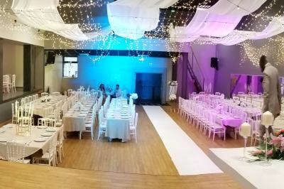 Lit double avec draps blancs, coussins décoratifs noirs et blancs, lampe de chevet allumée et tableau mural coloré.