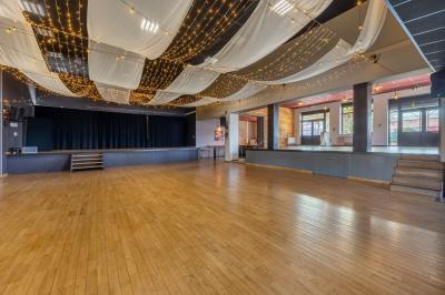 Lit double avec draps blancs, coussins décoratifs noirs et blancs, lampe de chevet allumée et tableau mural coloré.