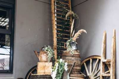 Salon lumineux avec canapé et fauteuils rayés, table basse en rotin, plante verte et grande fenêtre avec rideaux blancs.