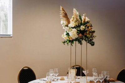 Salon lumineux avec canapé et fauteuils rayés, table basse en rotin, plante verte et grande fenêtre avec rideaux blancs.