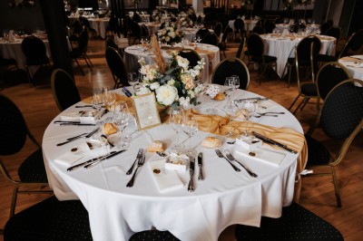 Salon lumineux avec canapé et fauteuils rayés, table basse en rotin, plante verte et grande fenêtre avec rideaux blancs.