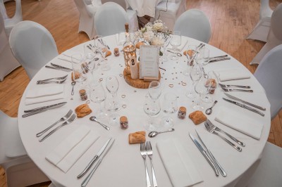 Salon lumineux avec canapé et fauteuils rayés, table basse en rotin, plante verte et grande fenêtre avec rideaux blancs.