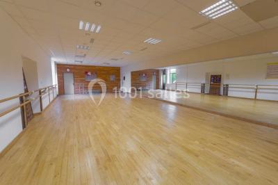 Vue d'un jardin avec allée gravillonnée, haies taillées, pelouse et arbres en arrière-plan sous un ciel dégagé.