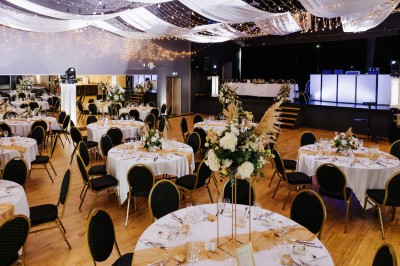 Salon lumineux avec canapé et fauteuils rayés, table basse en rotin, plante verte et grande fenêtre avec rideaux blancs.