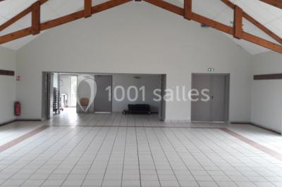 Cuisine professionnelle avec plan de travail en inox, cuisinière équipée et hotte, éclairée par une fenêtre.