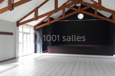 Cuisine professionnelle avec plan de travail en inox, cuisinière équipée et hotte, éclairée par une fenêtre.