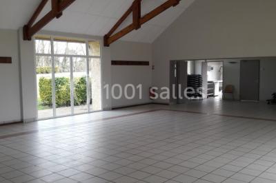 Cuisine professionnelle avec plan de travail en inox, cuisinière équipée et hotte, éclairée par une fenêtre.