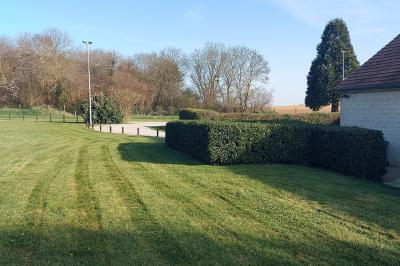 Cuisine professionnelle avec plan de travail en inox, cuisinière équipée et hotte, éclairée par une fenêtre.
