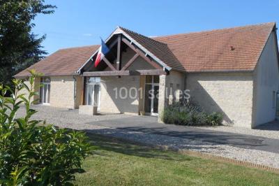 Cuisine professionnelle avec plan de travail en inox, cuisinière équipée et hotte, éclairée par une fenêtre.