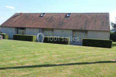 Cuisine professionnelle avec plan de travail en inox, cuisinière équipée et hotte, éclairée par une fenêtre.