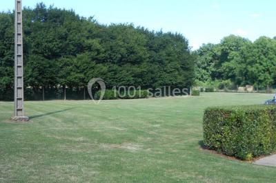 Cuisine professionnelle avec plan de travail en inox, cuisinière équipée et hotte, éclairée par une fenêtre.