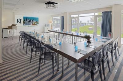 Salle de restaurant lumineuse avec tables dressées, chaises violettes, luminaires dorés et grandes baies vitrées.
