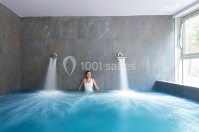 Salle de restaurant lumineuse avec tables dressées, chaises violettes, luminaires dorés et grandes baies vitrées.