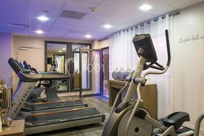 Salle de restaurant lumineuse avec tables dressées, chaises violettes, luminaires dorés et grandes baies vitrées.
