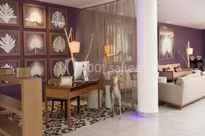 Salle de restaurant lumineuse avec tables dressées, chaises violettes, luminaires dorés et grandes baies vitrées.